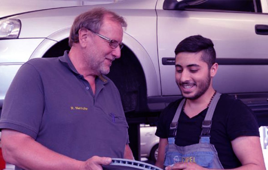 Garage-owner Robert Menhofer (L) and Syrian refugee George Romanos talk at a workshop in Bobingen, southern Germany