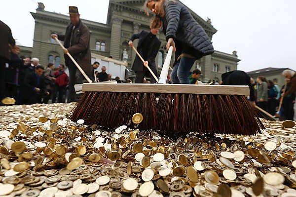 Supporters of Generation Basic Income sweep away Swiss coins in Bern. The group just filed a referendum to Swiss voters guaranteeing Swiss adults a basic income. (Image Source: Reuters)