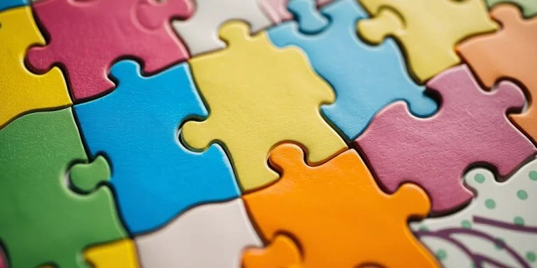 Colorful jigsaw puzzle pieces interlocked with missing sections.