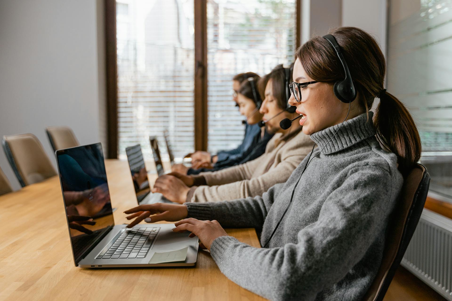 Customer support reps working on laptops and sitting at a table.