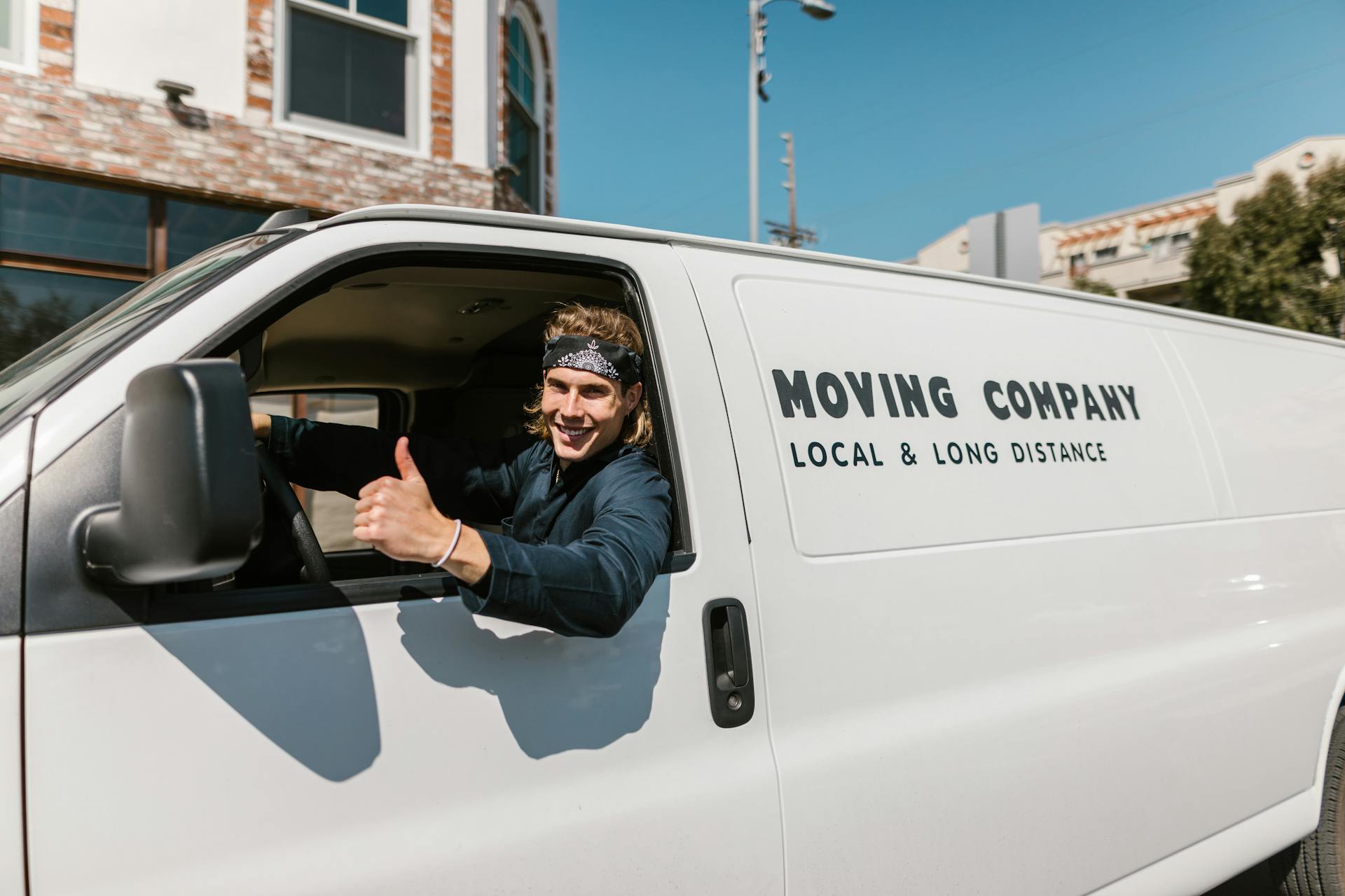 A man smiling in a van that says, “Moving company: local & long distance.