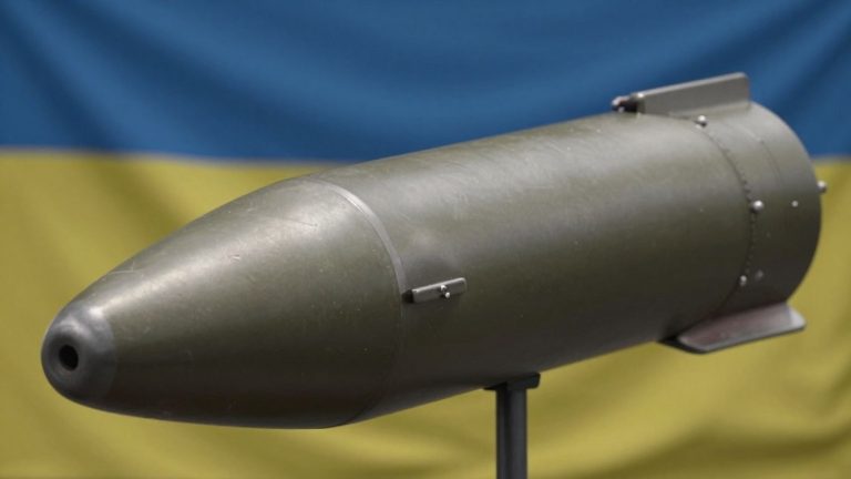 155mm artillery shell with Ukrainian flag in background.